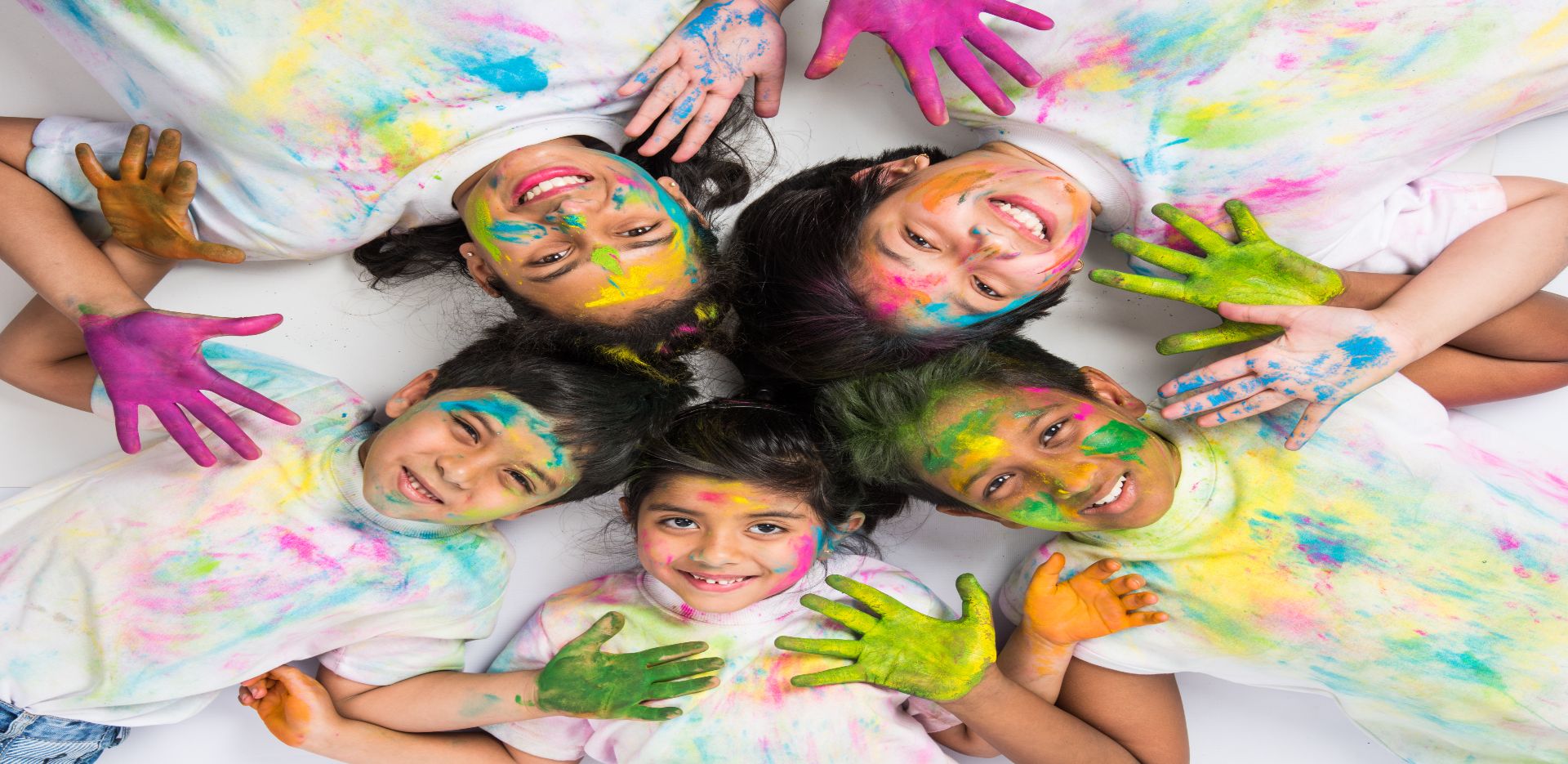 Children pose with colour-smeared hands on Holi